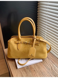 Sac Boston jaune moutarde givré avec poignées en cuir lisse et bandoulière sur un bureau