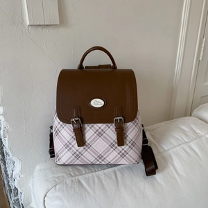 Detail view of pink plaid fabric and brown leather flap with bunny badge backpack