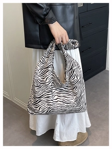 Detail view of stylish zebra print canvas tote bag carried by a model in a urban setting