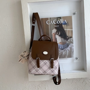 Detail view of pink plaid backpack featuring a brown flap and a plush bear charm