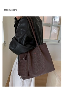 Detailed view of large burgundy tote bag with vintage texture and matching pouch on model