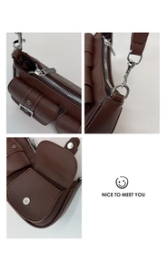 Macro shot of silver zippers and hardware on deep brown pebbled leather shoulder bag