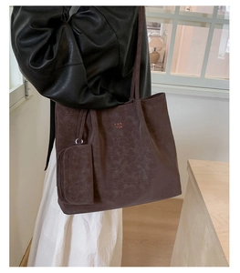 Detail of dark brown tote bag with vintage leather texture and mini pouch attachment