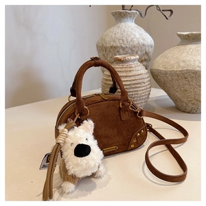 Detail of vintage brown faux suede bowling bag with cute plush puppy charm and hardware