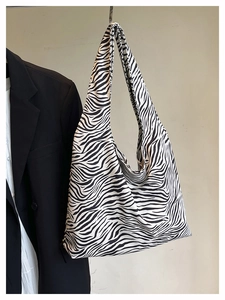 Detailed view of fashionable zebra pattern tote bag with wide shoulder strap on a hanger