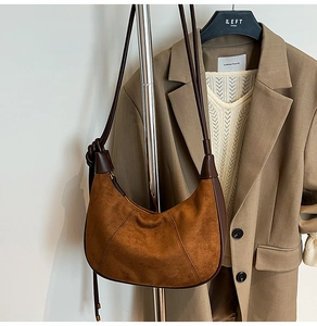 Close-up of brown suede hobo bag with dark leather edges shown on a clothing hanger
