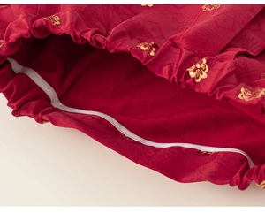 Detail of red festive Chinese New Year cloak with gold flower pattern and elastic trim