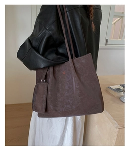 Macro view of dark brown vintage leather tote bag with brand logo and matching coin purse