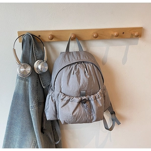 Detail view of lightweight gray nylon backpack with drawstring pocket in a cozy home setting