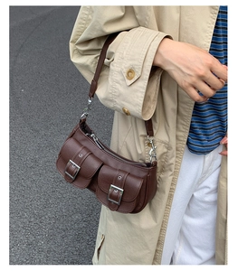 Deep brown lychee textured leather underarm bag with double flap pockets on a beige coat