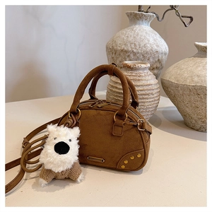 Detail of vintage brown suede bowling bag with metal studs and cute plush dog charm