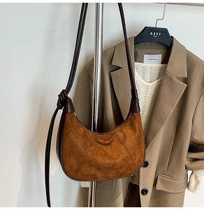Detail of a brown suede crescent bag with leather trim and knotted strap design