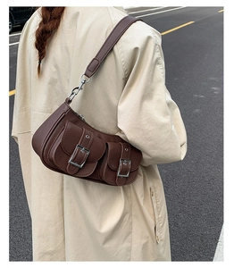Detail of a dark coffee leather shoulder bag with double pockets and vintage silver buckles