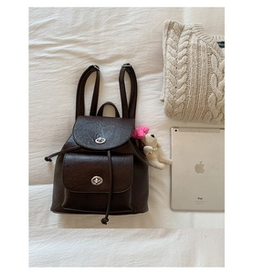 Detail eines kaffeebraunen Vintage-Lederrucksacks mit silbernen Drehverschlüssen und Anhänger