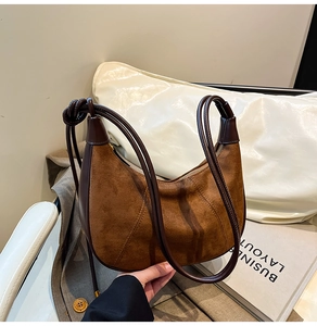 Close-up of brown suede hobo bag with knotted leather strap and smooth top zipper