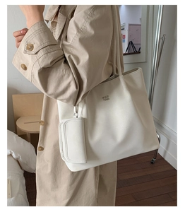Detail of minimalist cream white tote bag set with metal brand logo and coin purse accessory
