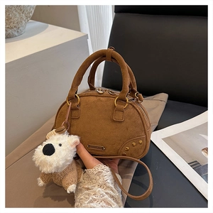 Detailed view of the brown suede bowling bag with a cute white dog plush pendant