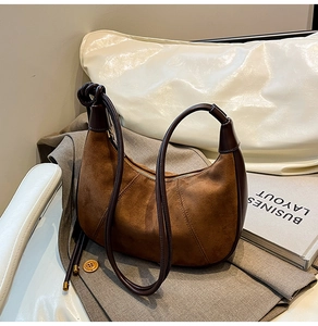 Detailed macro view of vintage brown suede crescent bag with dark leather trim and stitching