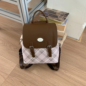 Detail view of pink plaid fabric and brown leather flap with bunny patch on backpack