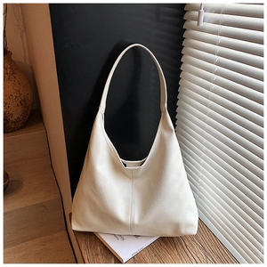 Nahaufnahme der weißen Oversized-Tasche mit Lychee-Ledertextur auf einer Holzplatte