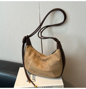 Close-up of retro suede hobo bag with knotted strap and premium leather details