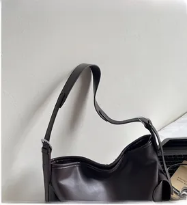 Detailed view of the wide shoulder strap and silver metal buckle on the dark brown tote bag
