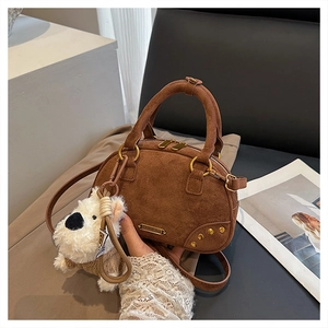 Detail of vintage brown suede bowling bag with gold zippers and white plush dog charm