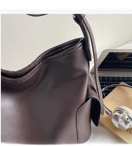 Detail of a dark brown hobo tote bag featuring a side pocket and smooth leather texture