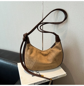 Detail of khaki suede crescent bag featuring brown leather trim and knotted cord strap