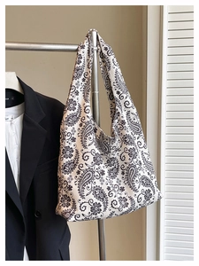 Detailed view of paisley pattern tote bag hanging next to business attire styling
