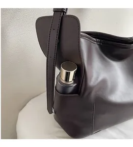 Detailed close-up of the functional side pocket on this dark brown leather tote bag