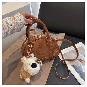 Detail of vintage brown suede bowling bag with cute plush puppy charm and golden hardware
