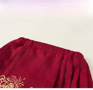 Detail of red Chinese style skirt featuring elastic waist and golden floral embroidery