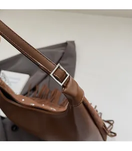 Dettaglio della fibbia d'argento e delle lunghe frange sulla borsa marrone chic