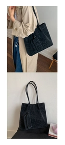 Detail of a large black vintage leather tote bag with long straps and mini pouch