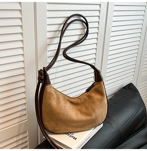 Detailed shot of brown suede hobo bag featuring a knotted strap and leather stitching