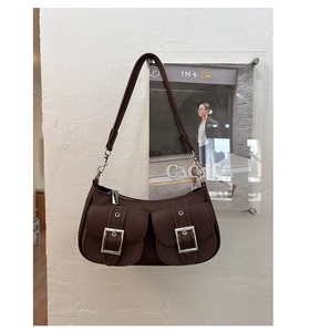 Close-up of brown textured leather underarm bag with metal buckles and vintage pockets