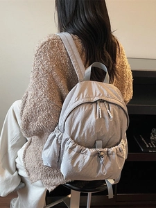 Minimalist light grey nylon backpack for women featuring a drawstring front pocket and dual zippers