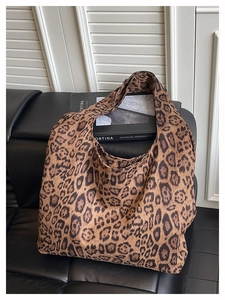 Detail view of leopard print tote bag on leather sofa showcasing soft texture and large capacity