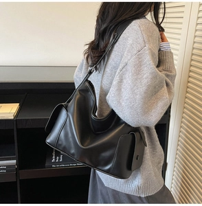Detail view of a large black vintage hobo bag showing shoulder strap fit and side pockets