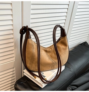 Detailed close-up of brown suede hobo bag with knotted leather strap on white books