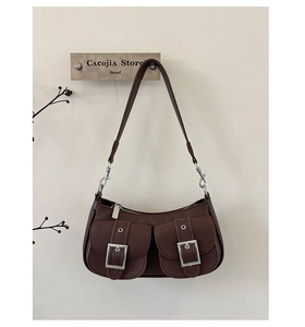Detail of a brown vintage leather underarm bag featuring dual front buckle pockets