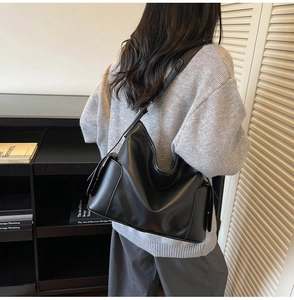 Detail of a black hobo shoulder bag featuring side pockets and spacious leather texture