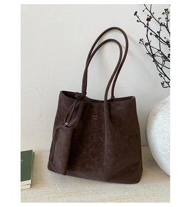 Detail of a large coffee brown tote bag with retro matte texture and logo pendant