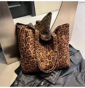 Dettaglio della grande borsa tote leopardata con giacca di pelle e oggetti decorativi