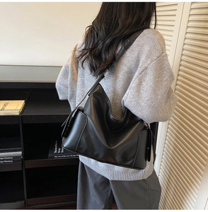 Detailed back view of a large black matte leather tote bag worn by a model for daily commute