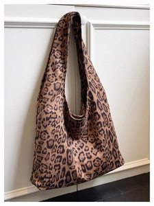 Detailed close-up of large leopard print tote bag hanging on a white cabinet handle