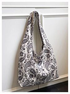 Close-up of black and white paisley pattern cotton tote bag hanging on a white cabinet