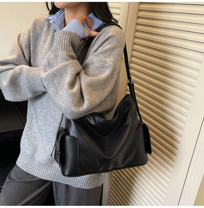 Detail view of black matte soft leather tote bag with functional buckle side pockets