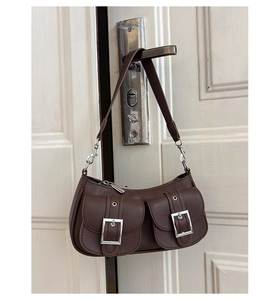 Macro detail of brown leather texture and silver buckle pockets on retro underarm bag